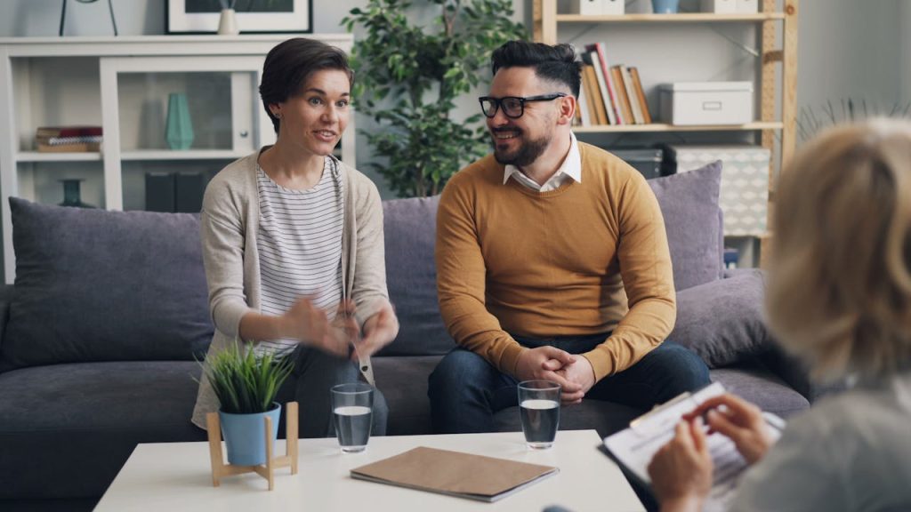 A couple discussing with a therapist during a counseling session indoors.